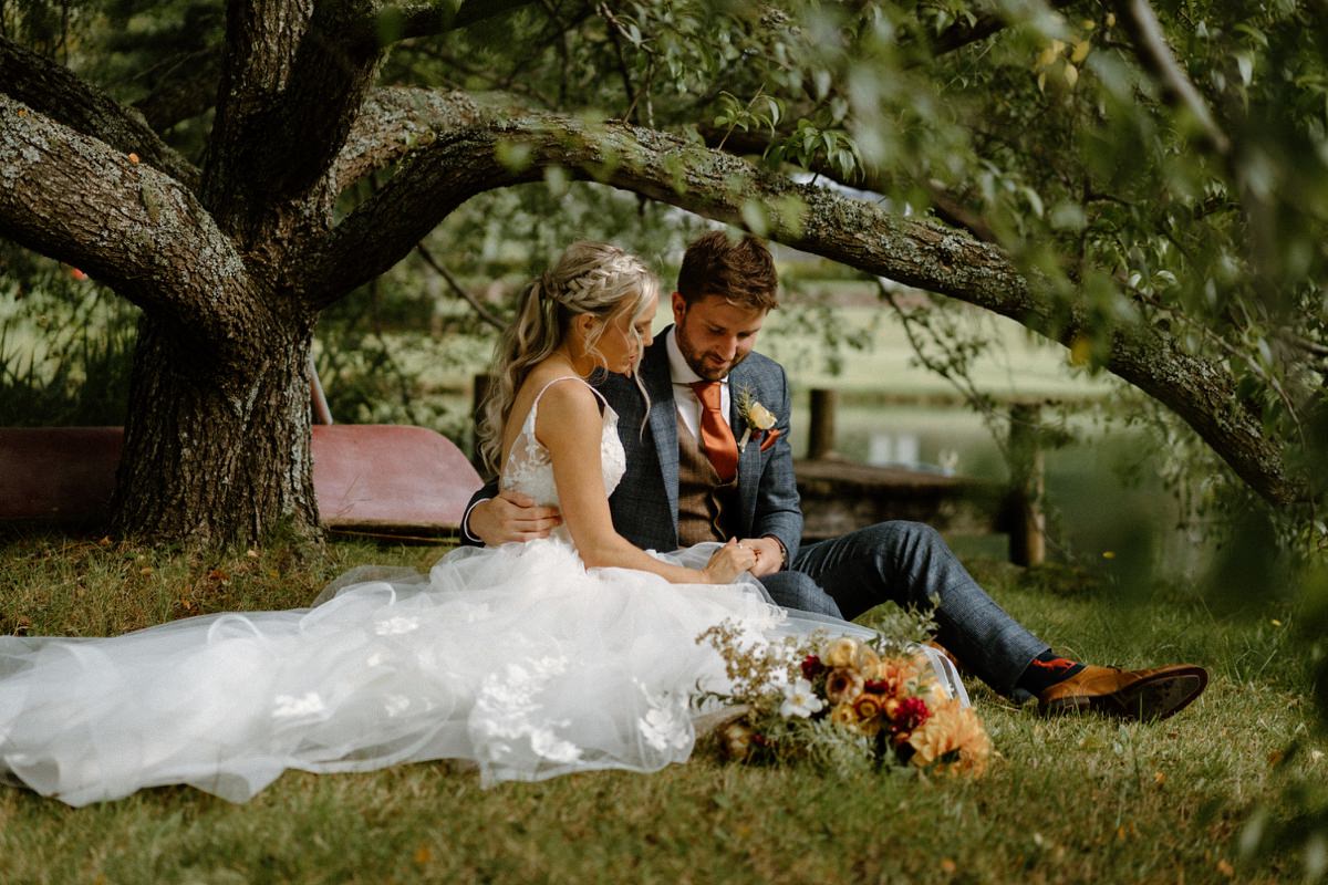 a newly wedded bride and groom cuddling under a willow tree at their bodycotts lane wedding