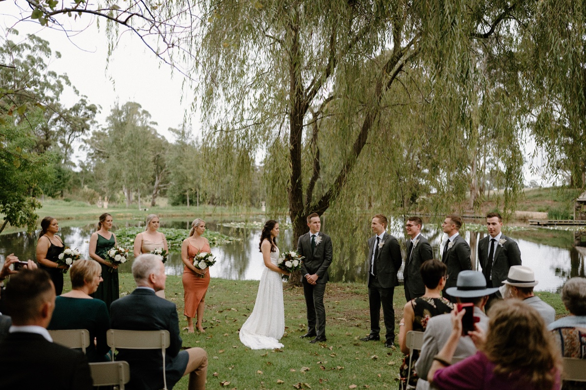 A bride and groom getting married in front of a willow tree at their Mali Brae Farm wedding.