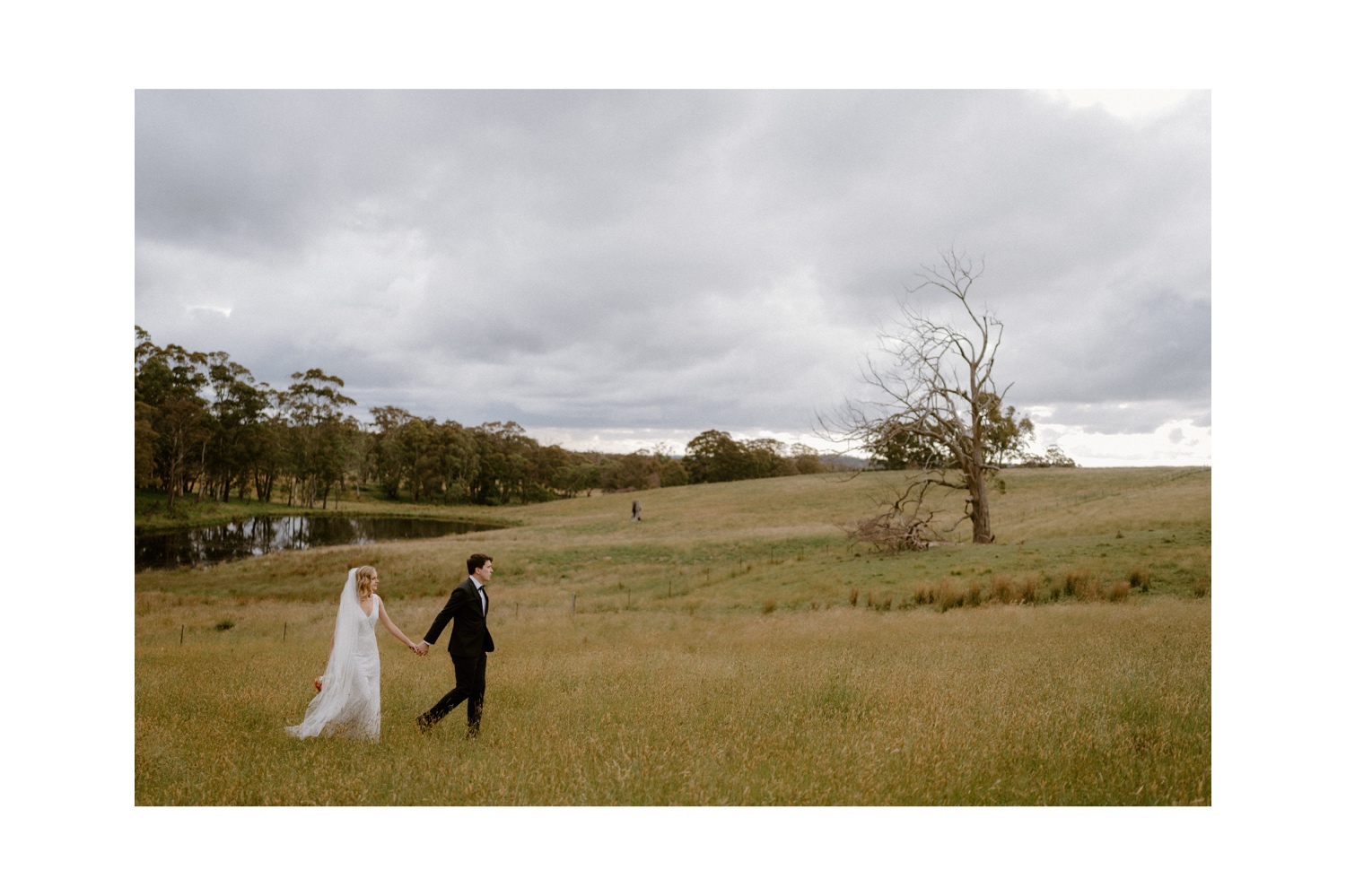 A bride and groom walking in an open field at their Mali Brae wedding.