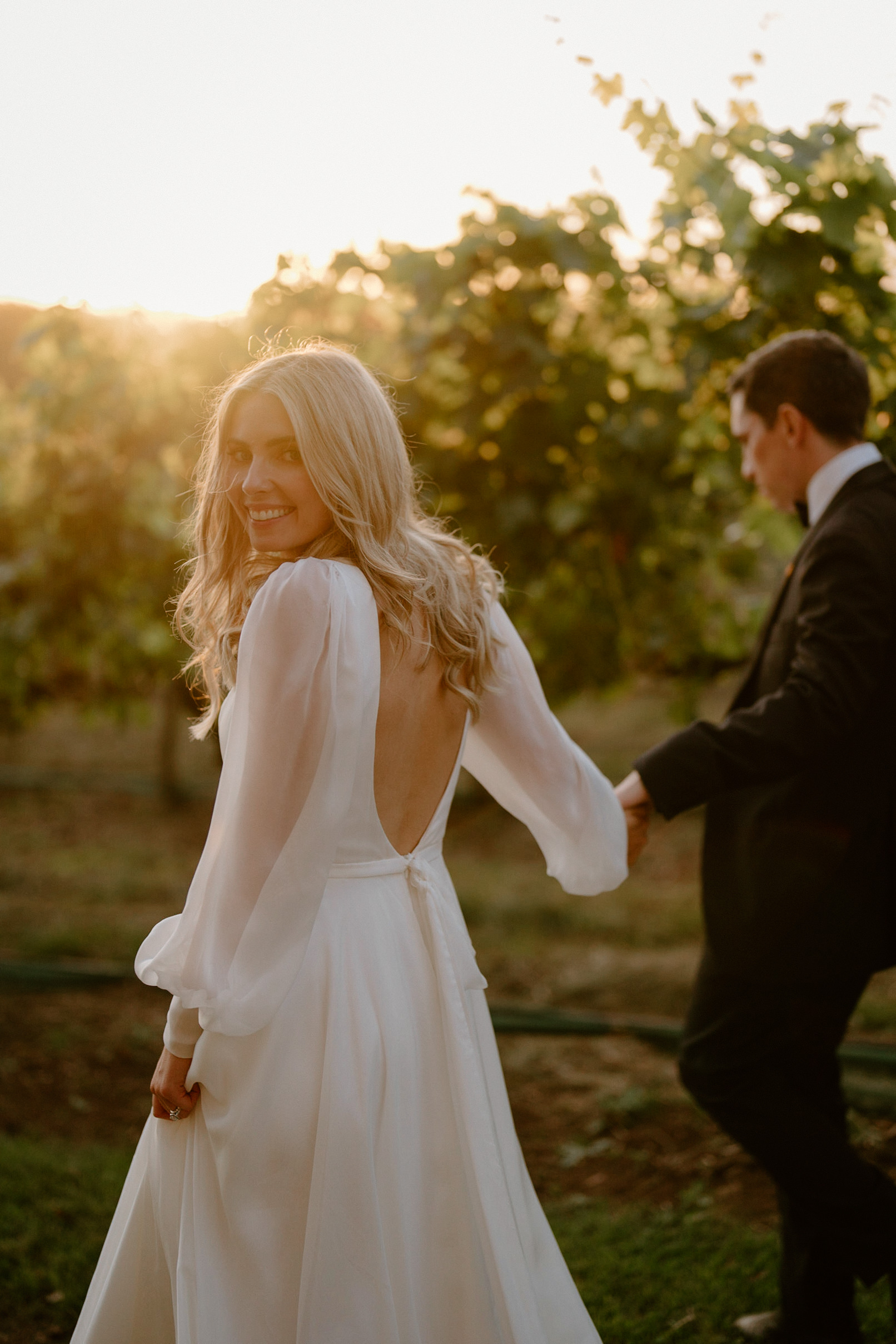 A bride and groom walking amongst the vineyards during sunset at their Centennial Vineyards wedding
