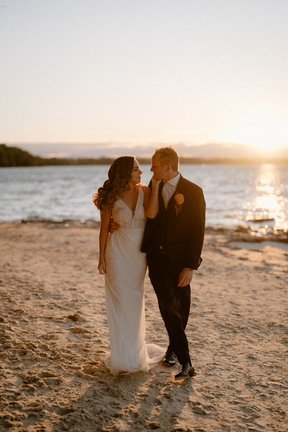 A stunning bride and groom walking on the beach at sunset for their Worrowing Jervis Bay wedding.