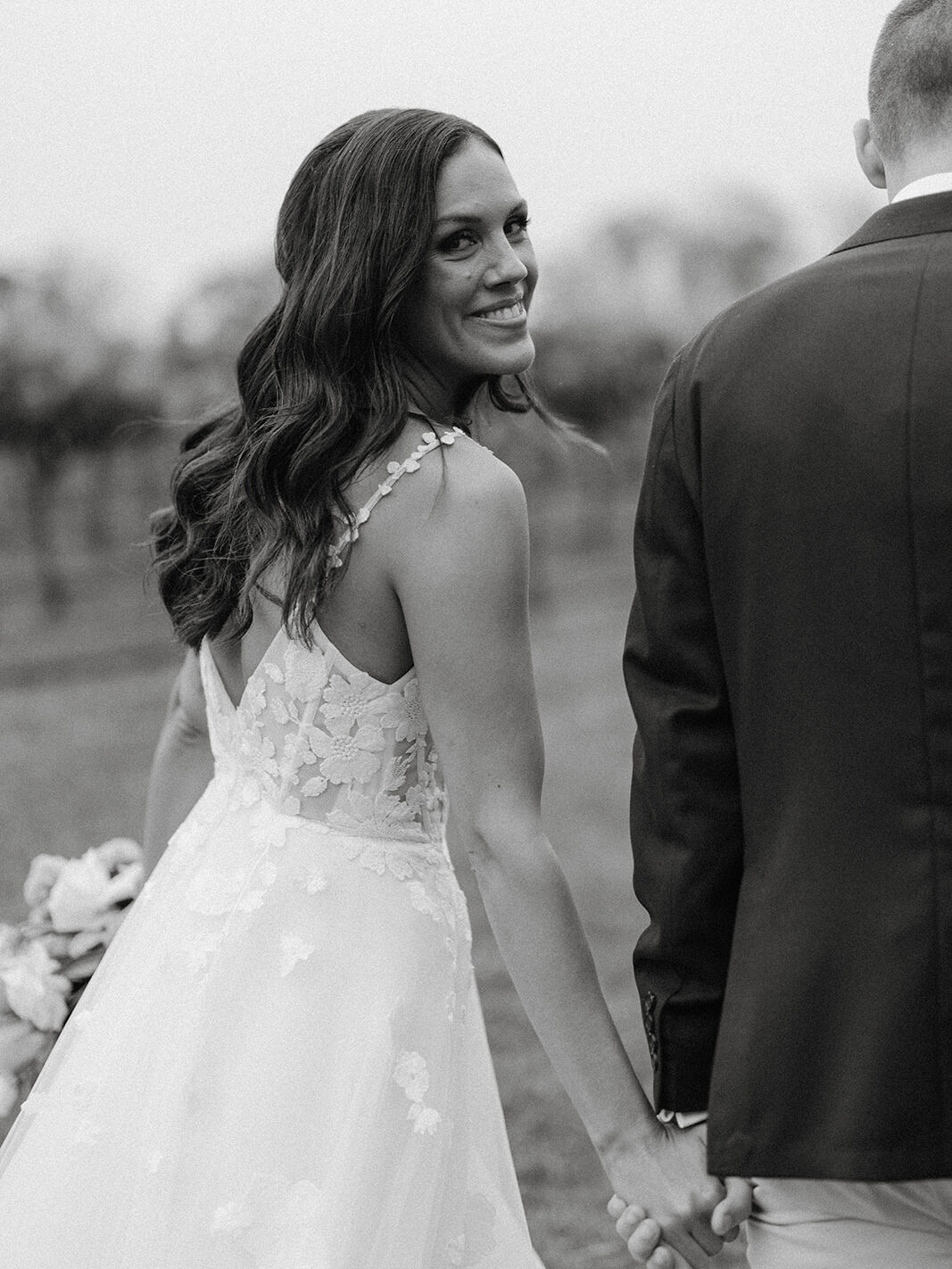 a bride looking back over her shoulder into the camera, happy as at her centennial vineyards restaurant wedding.