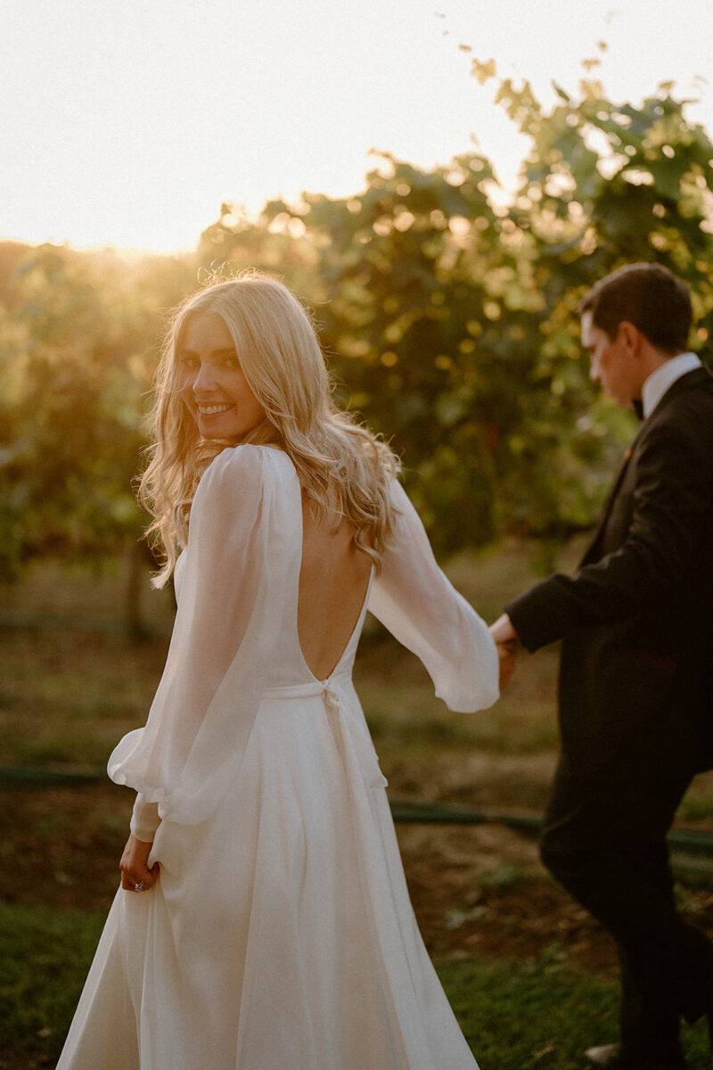 A bride looking back at southern highlands wedding photographer in a sunset.