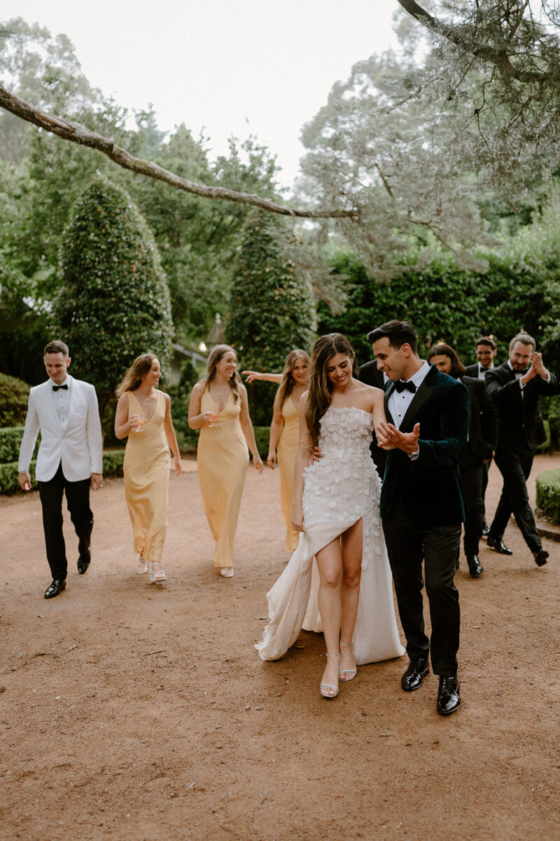 A bridal party walking towards the camera of south coast wedding photographer. They're all laughing and smiling while the groom is cuddling his wife.